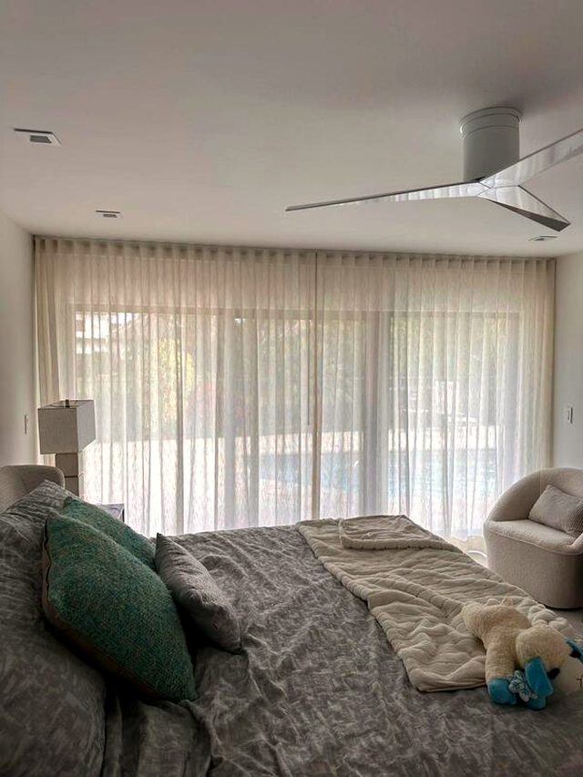 Primary bedroom, ocean side. Sheer on a bedroom slider: the glare goes and the view stays, which is the whole reason the room faces that way.