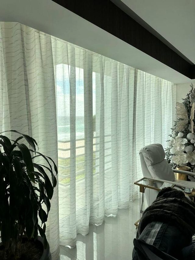 Textured sheer under a dropped beam. A weave with visible texture reads as fabric and not as film, which is the difference you feel in the room and not in the photo.